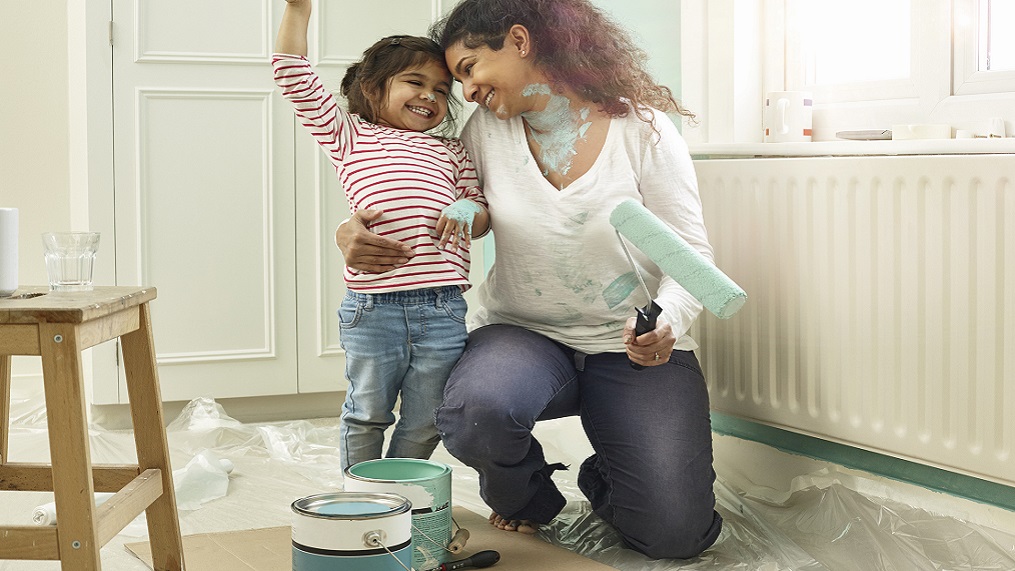 Woman and child smiling while painting a room  