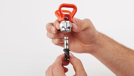 Two hands holding the spray tip insert piece